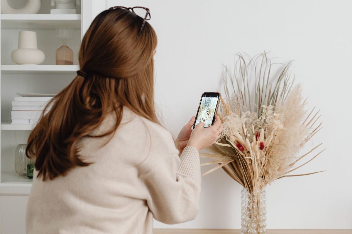 Vrouw neemt met haar smartphone een foto in een woonkamer
