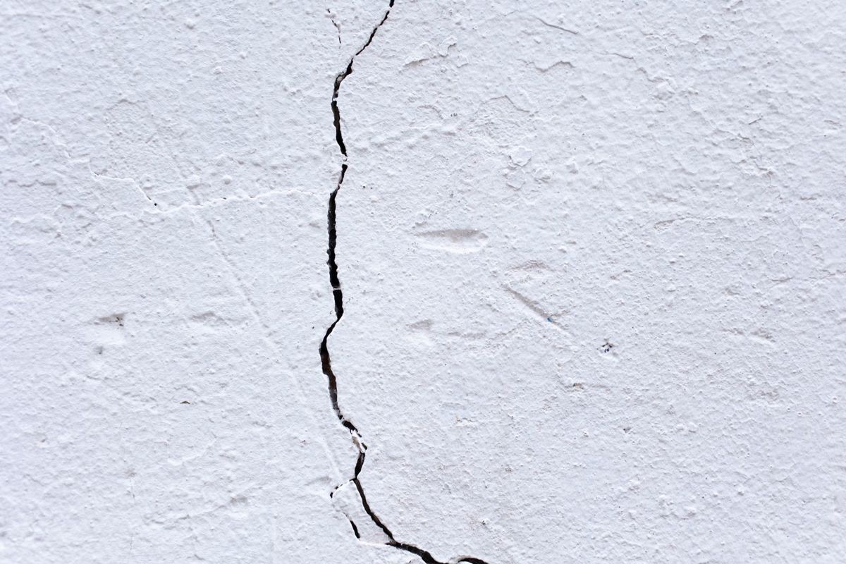 Pleisterwerk van een muur met een grote barst in het midden
